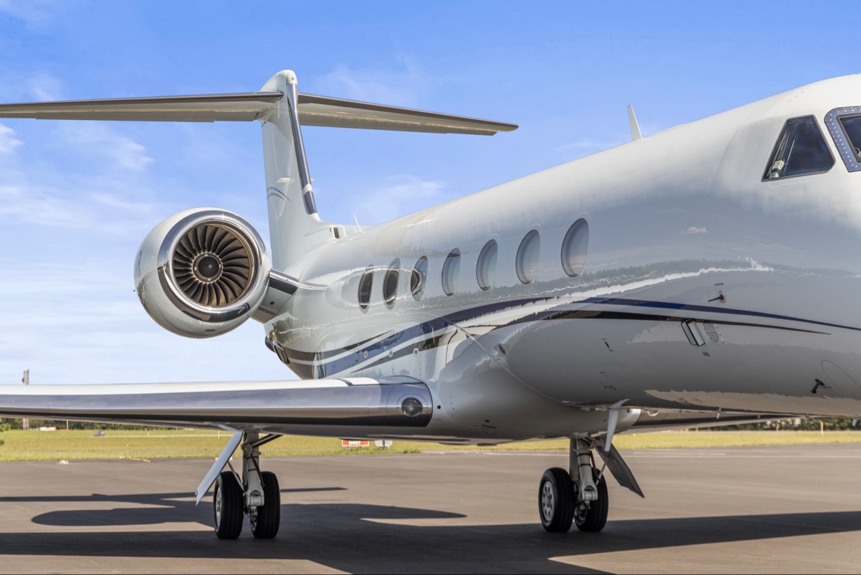 Private jet on the tarmac showing the tail, engine and cabin windows