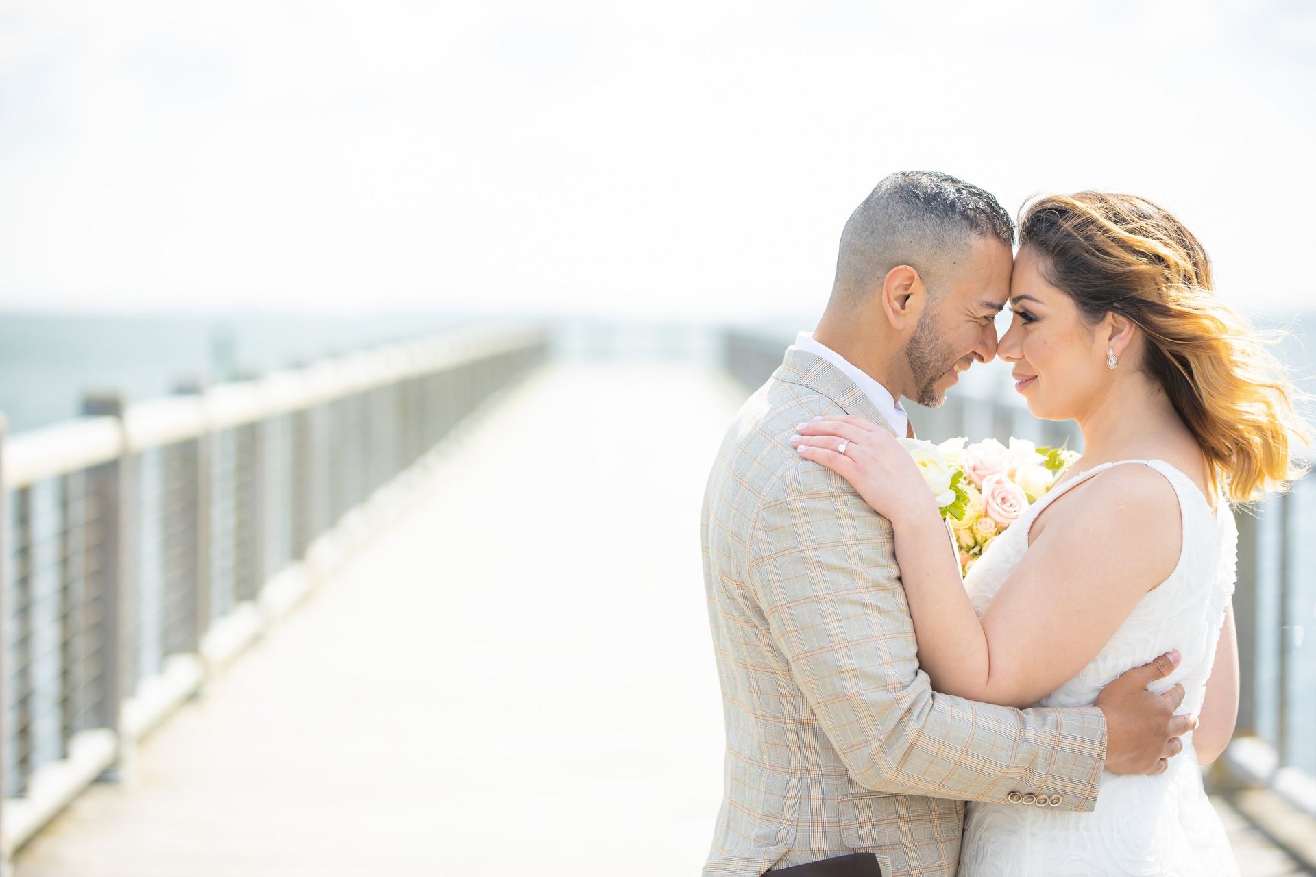 Bride and groom touching foreheads on a boardwalk