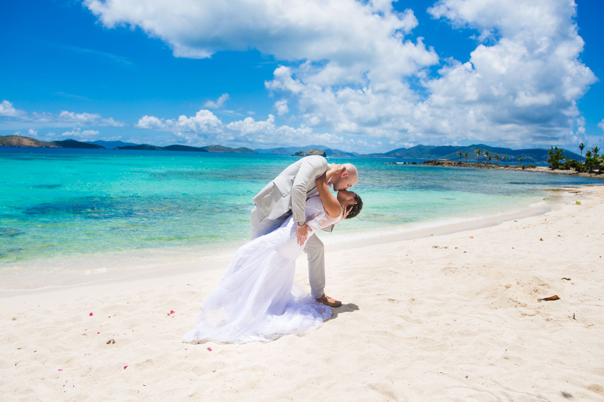 Newlyweds sharing a kiss on a turquoise-water beach