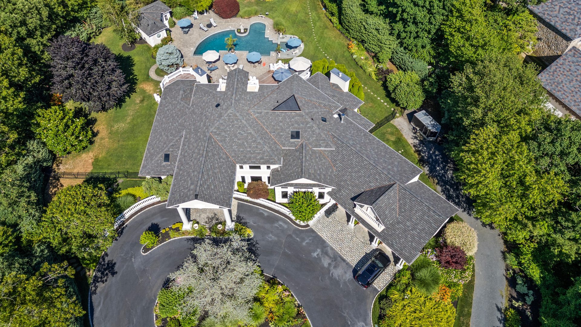 Completed shingle roof on an estate home with circular driveway, aerial view