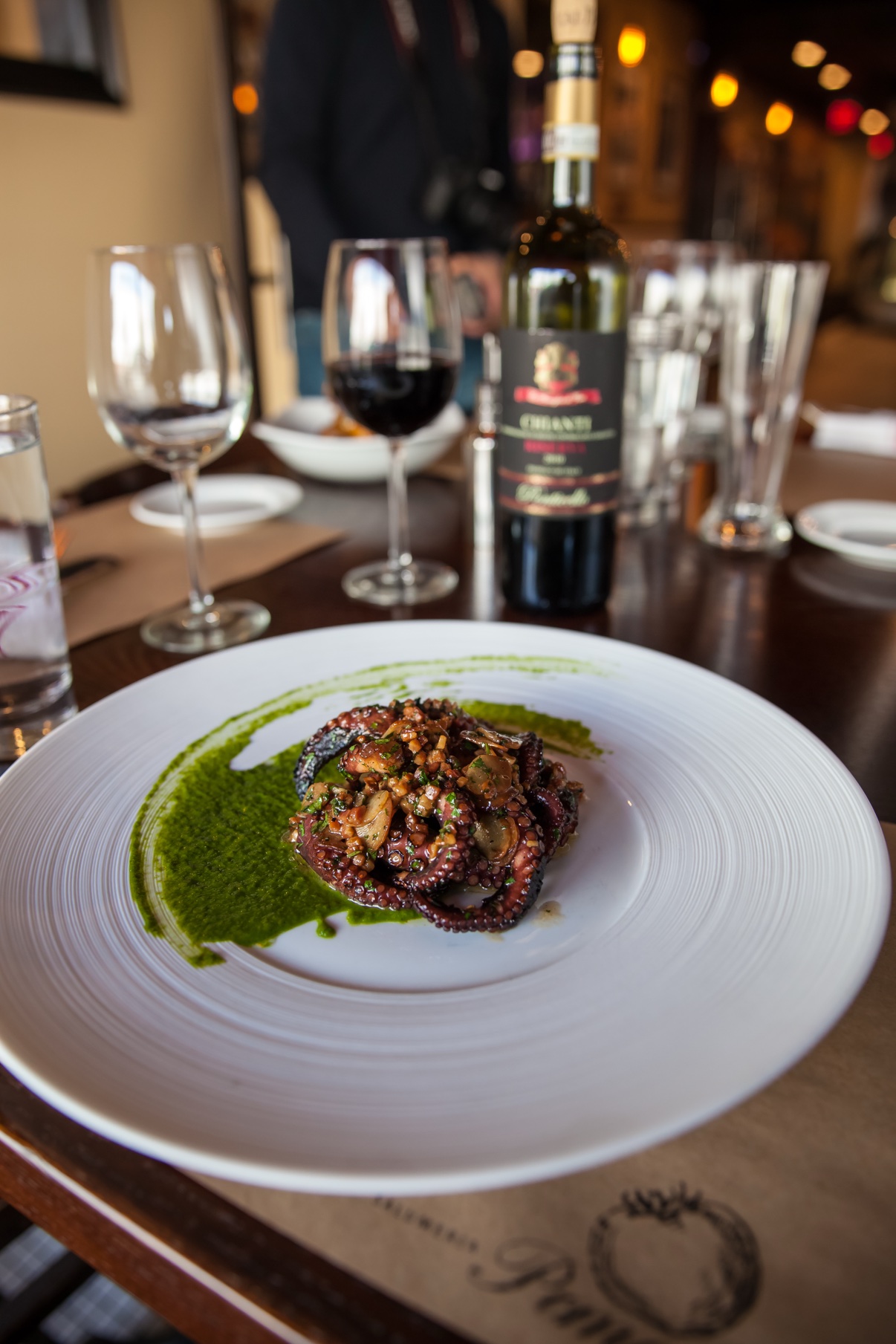 Grilled octopus with green sauce at a restaurant table