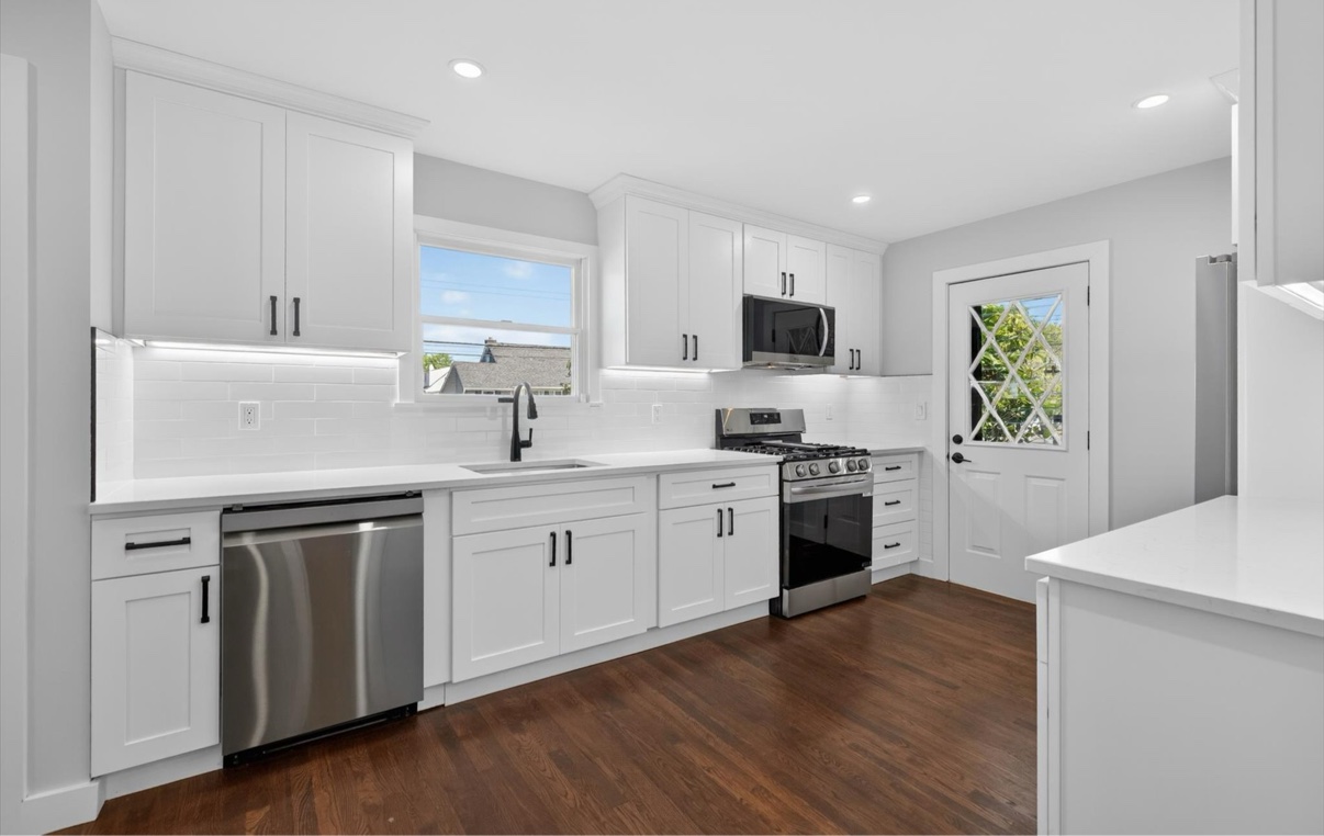 Bright kitchen with white cabinets, stainless appliances and a glass-paneled back door