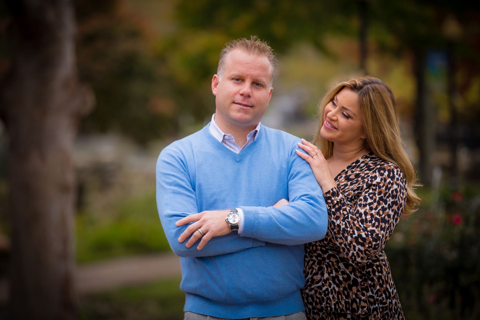 Couple portrait of a man in a blue sweater and a smiling woman in a leopard-print top outdoors