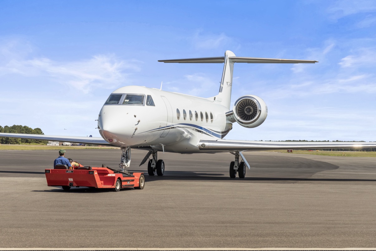 Private jet being towed on the tarmac by a tug cart