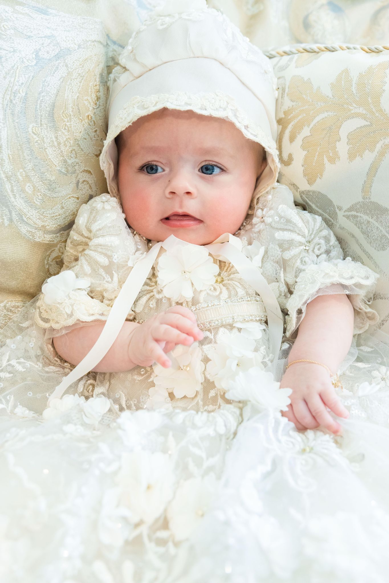 Baby in white gown on pillow