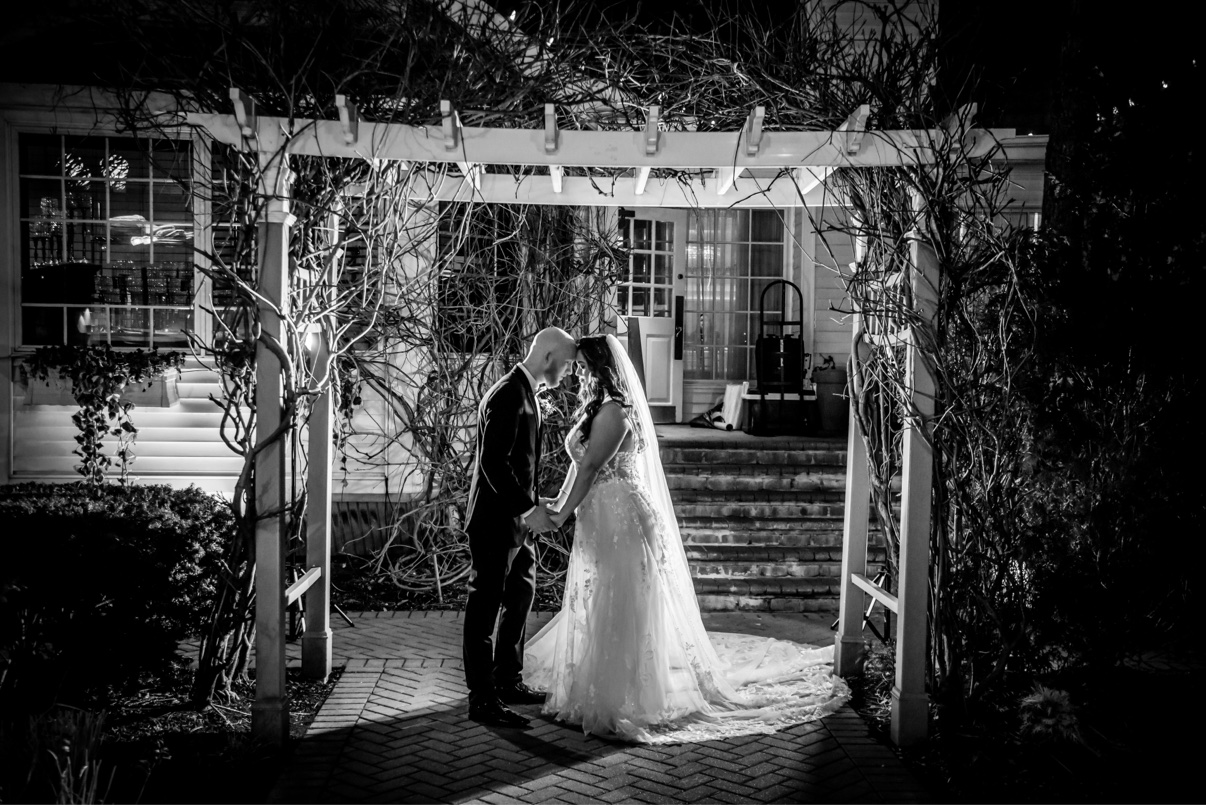 Newlyweds beneath a garden arbor at night