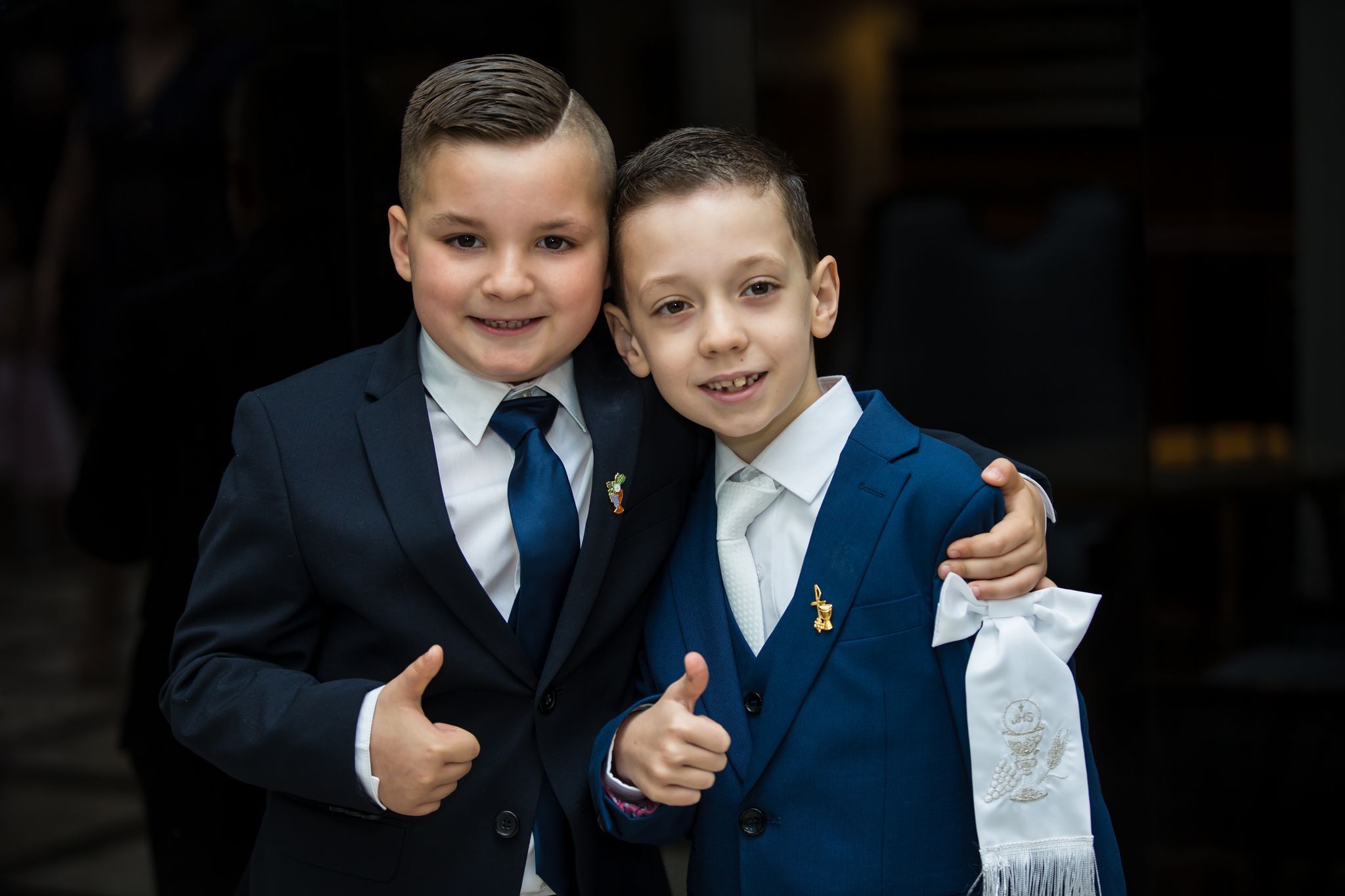 Two boys in communion suits giving thumbs up together