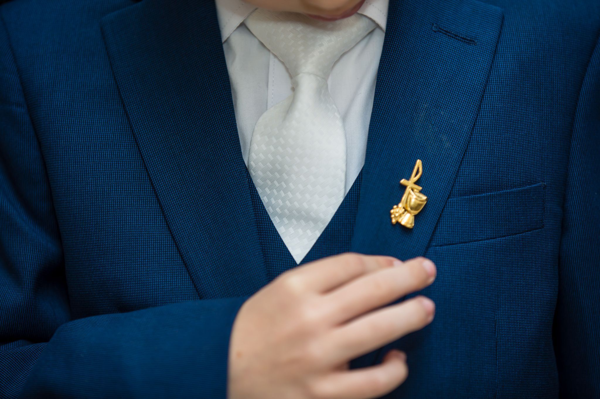 Gold chalice communion pin on blue suit lapel