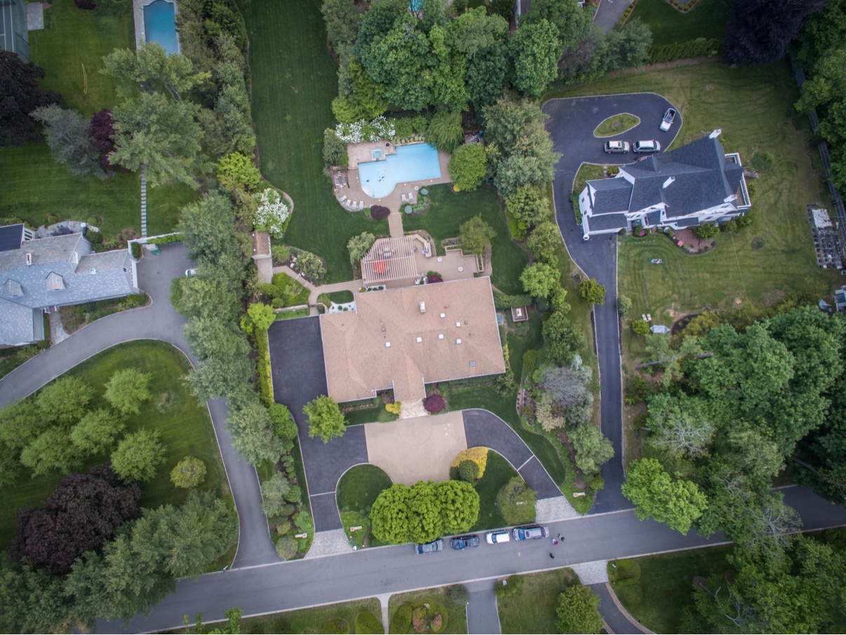 Aerial view of a ranch estate with a swimming pool and wraparound driveway