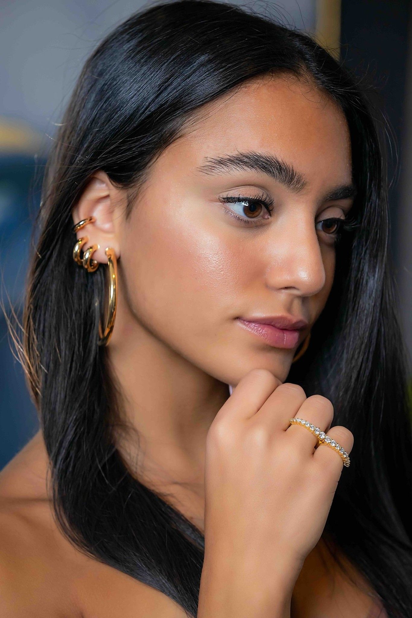 Model wearing gold hoop earrings and rings