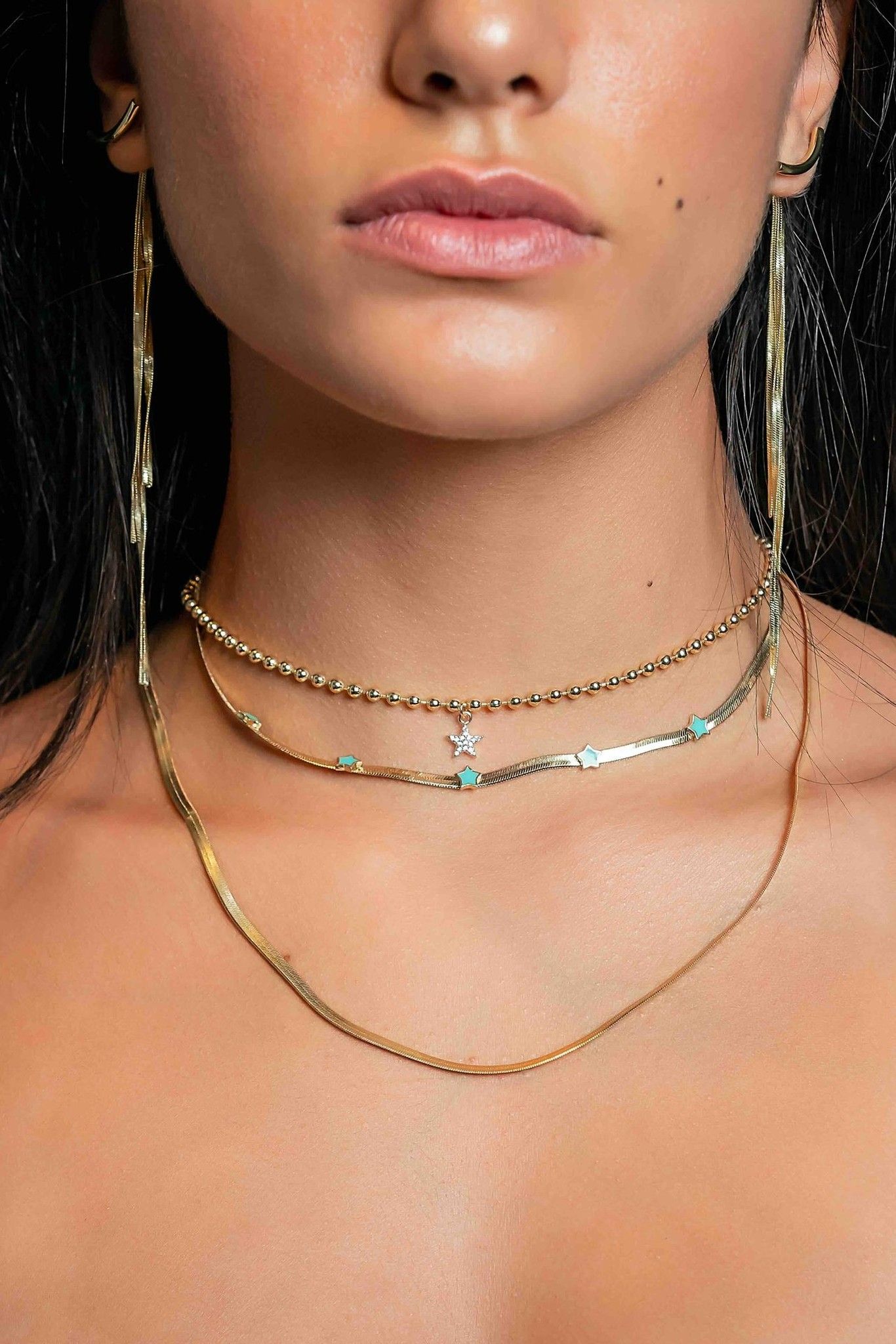 Model wearing layered gold necklaces close-up