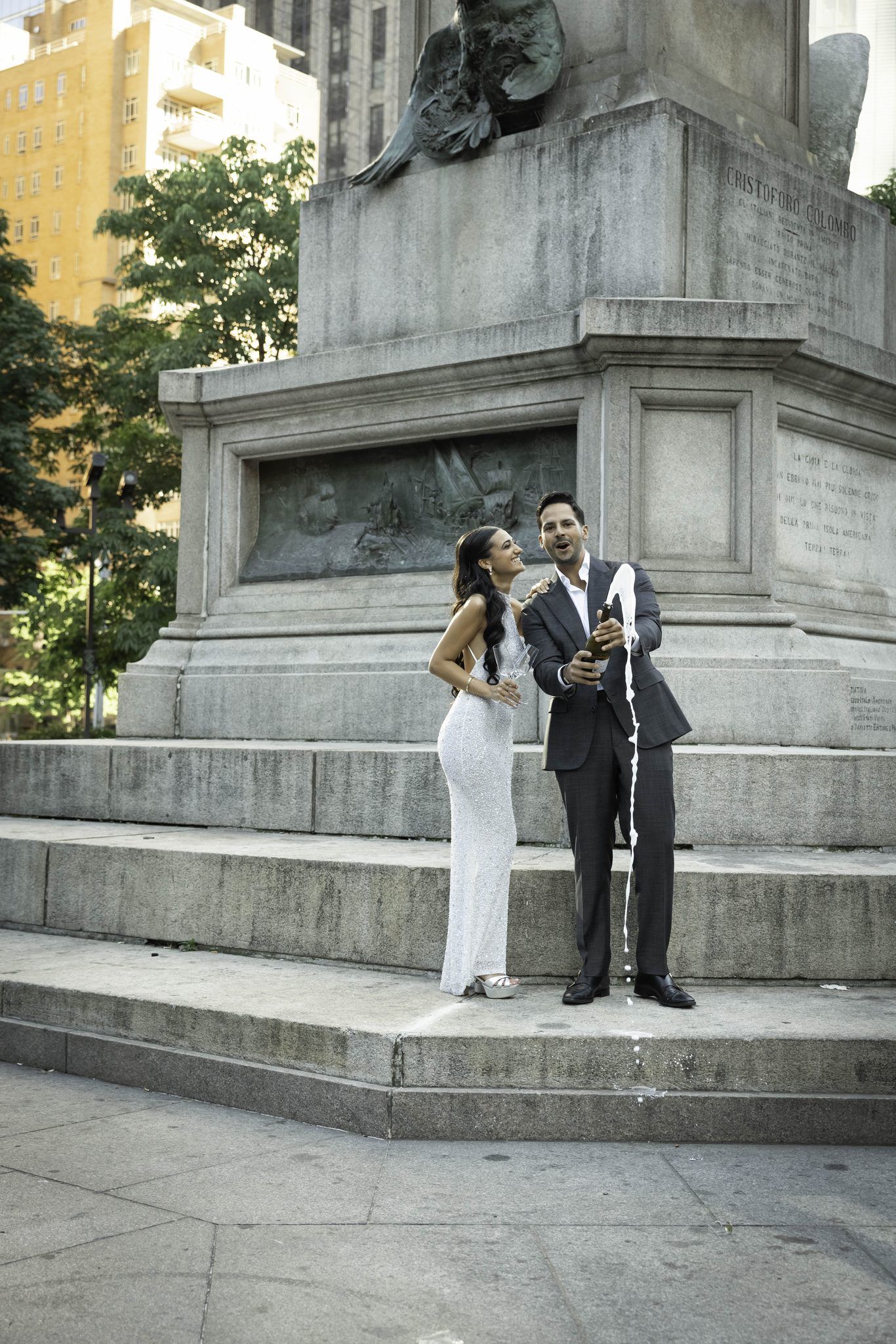 Couple popping champagne at a stone monument